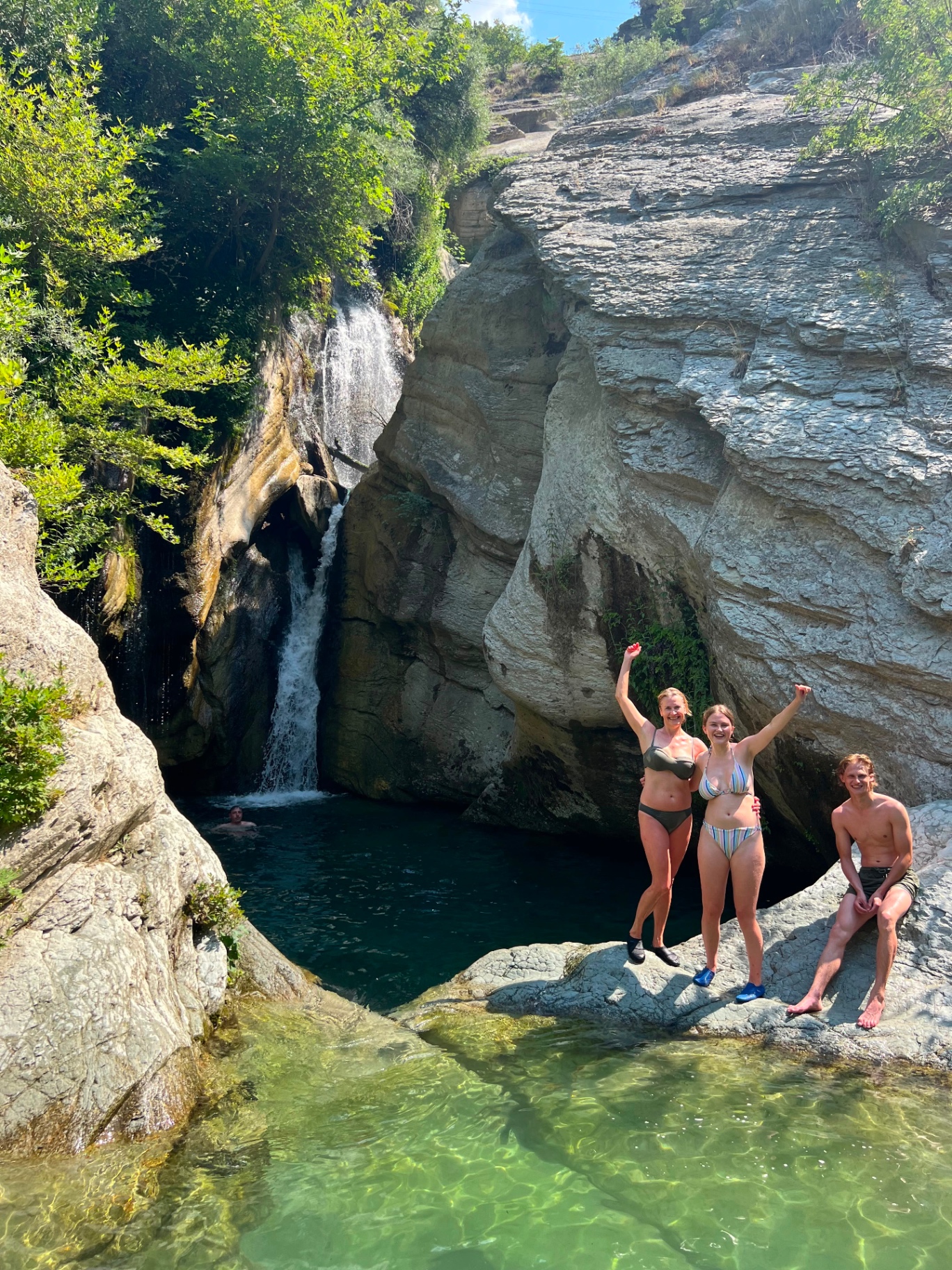 Travelers celebrating at the Bogova Waterfall pool