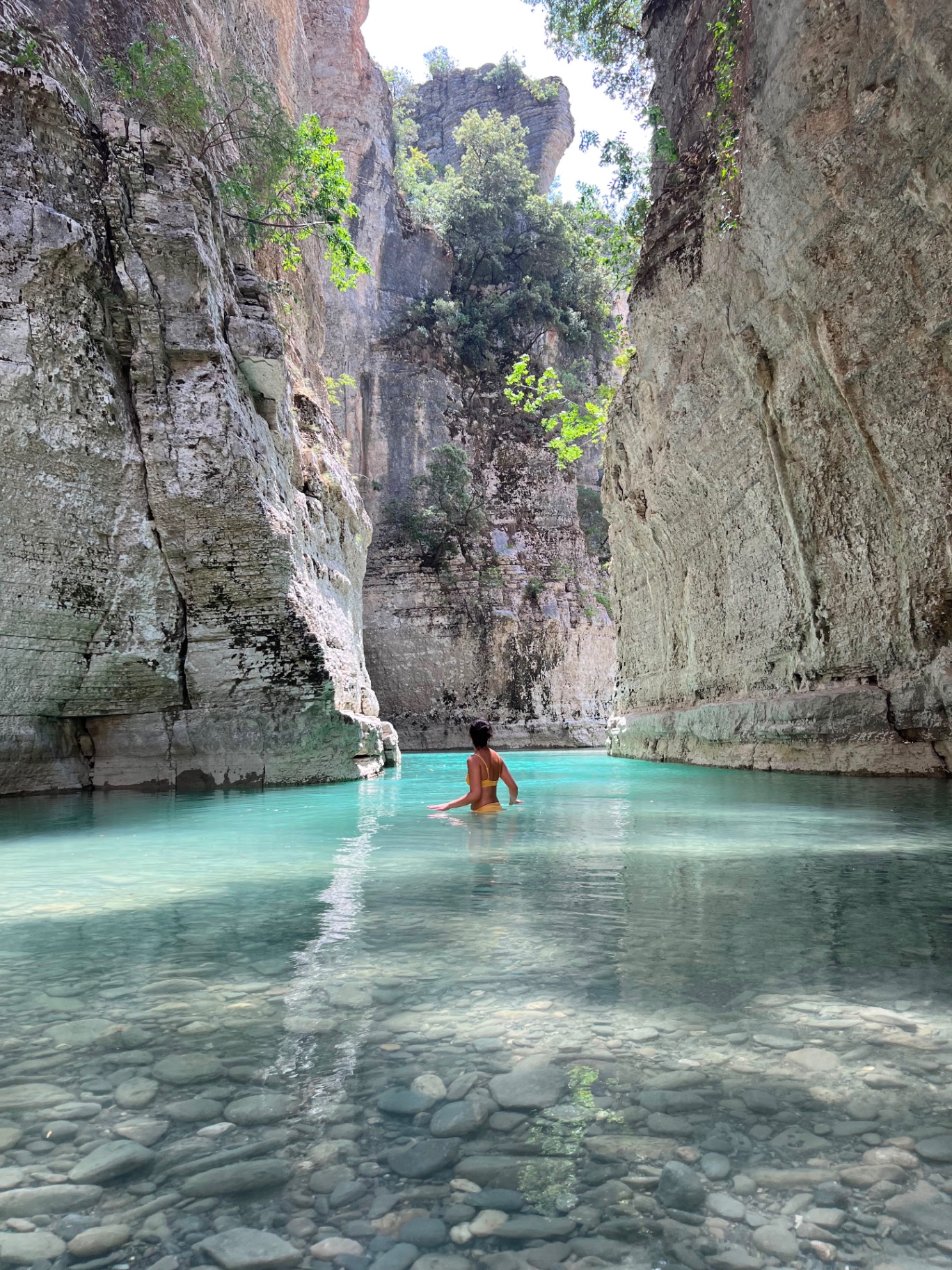 Person swimming in crystal clear turquoise canyon water