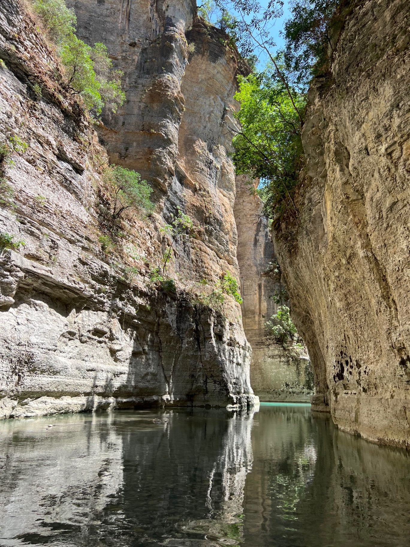 A traveler wading through turquoise water inside the towering Osumi Canyon